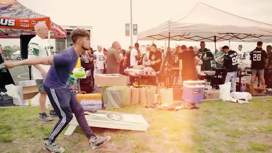A fan throwing at cornhole between the tailgate tents