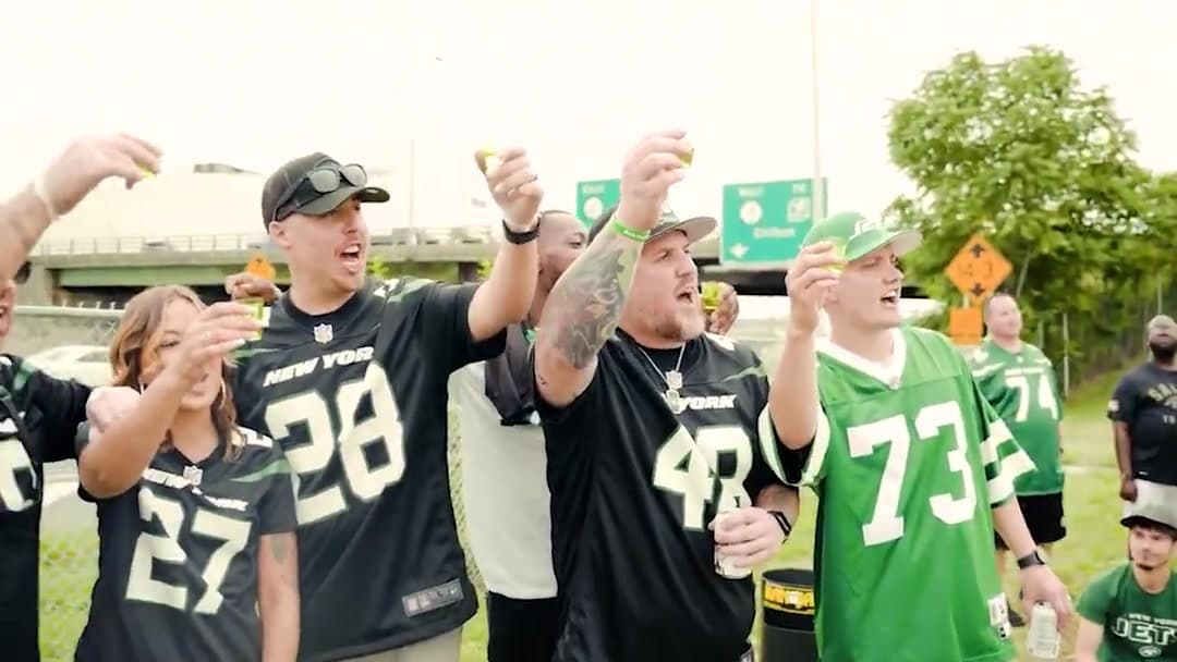 Jets fans in jerseys raising a toast at the tailgate